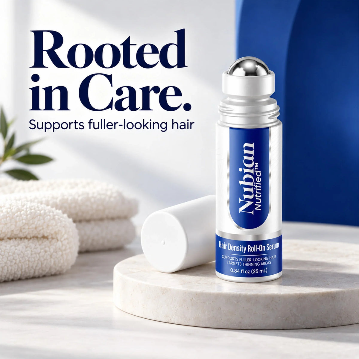 Nubian Nutrified Hair Density Roll-On Serum on a stone pedestal with white towels.